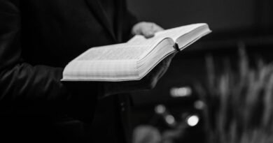 Grayscale close-up of a person holding an open Bible, conveying a sense of faith.