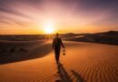 Pessoa caminhando em dunas de areia ao pôr do sol representando o deserto espiritual.